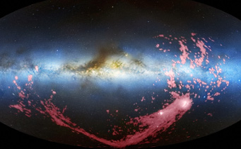 In this combined radio and visible-light image, the gaseous stream is shown in pink. The Milky Way is the light blue band in the center of the image. The Magellanic Clouds, satellite galaxies of the Milky Way, are the white regions at the bottom right. NRAO / AUI / NSF