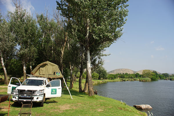Camping at the shore of the Vaal River, close to the center of the 300-kilometer Vredefort impact crater. The granite hills in the distance are part of the crater's central ring structure. 