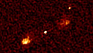 This view covers about 1% of the full MeerKAT first light image and shows a massive black hole in the distant universe — the matter falling into it produces the bright dot at the center — launching jets of powerful electrons moving at close to the speed of light that emit radio waves.    MeerKAT 