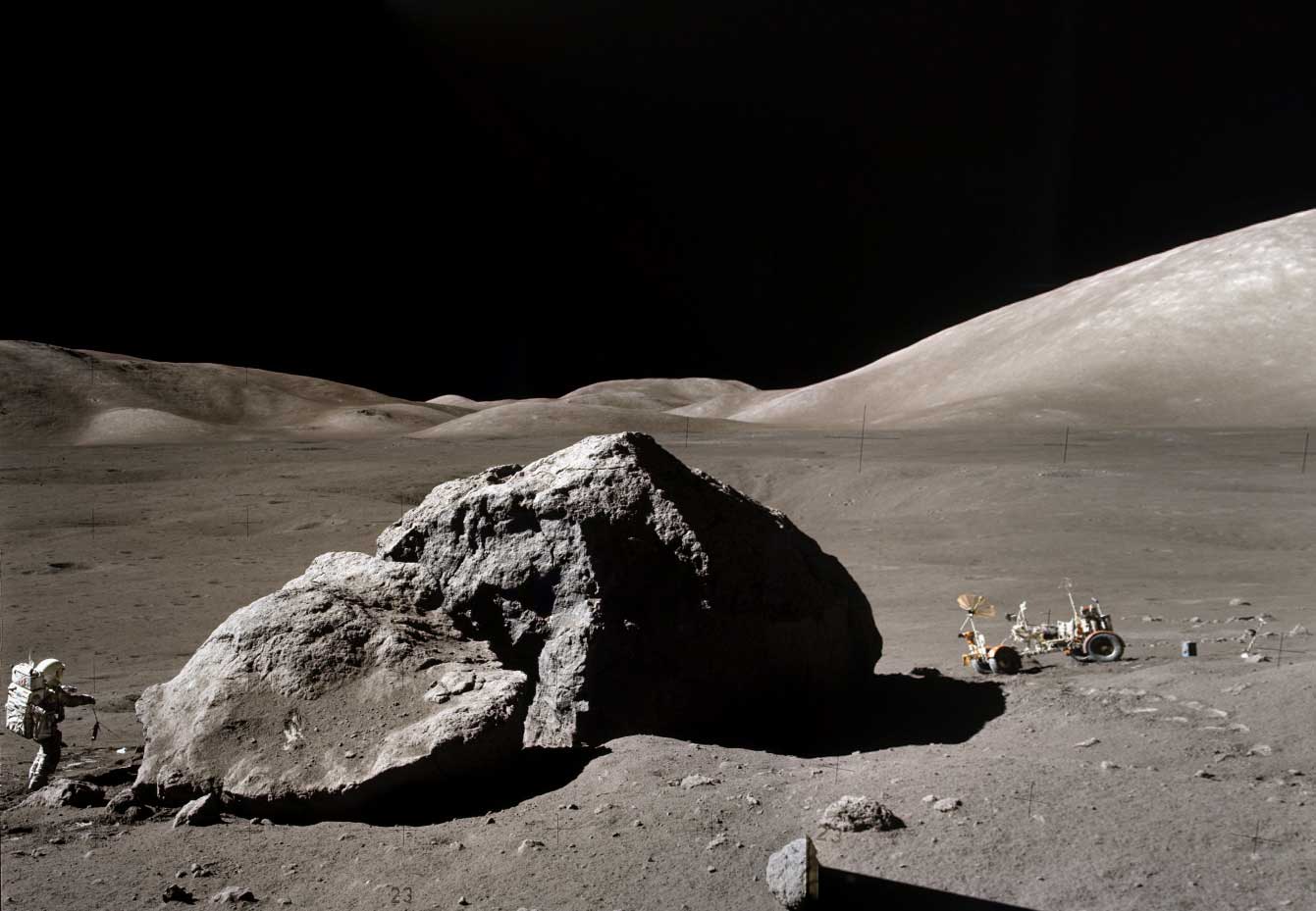 a large moon rock with an astronaut and vehicle next to it