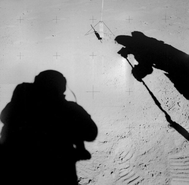 The shadows of two astronauts, one to the left and right, seem to be facing one another