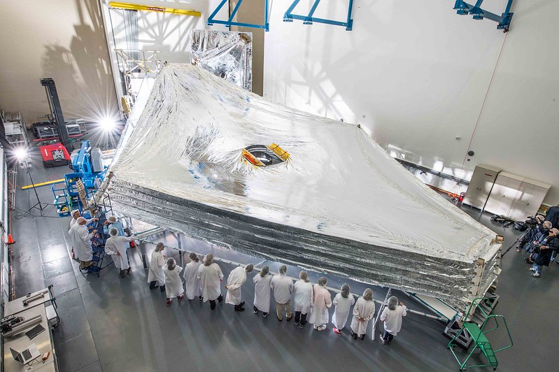 JWST sunshield deployed in a cleanroom with team members looking on