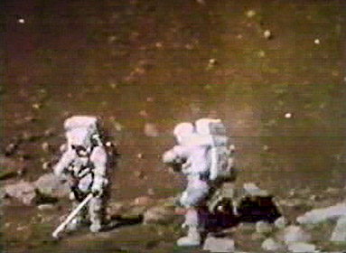 Two astronauts in the foreground appear to be standing at a boundary of rocks.