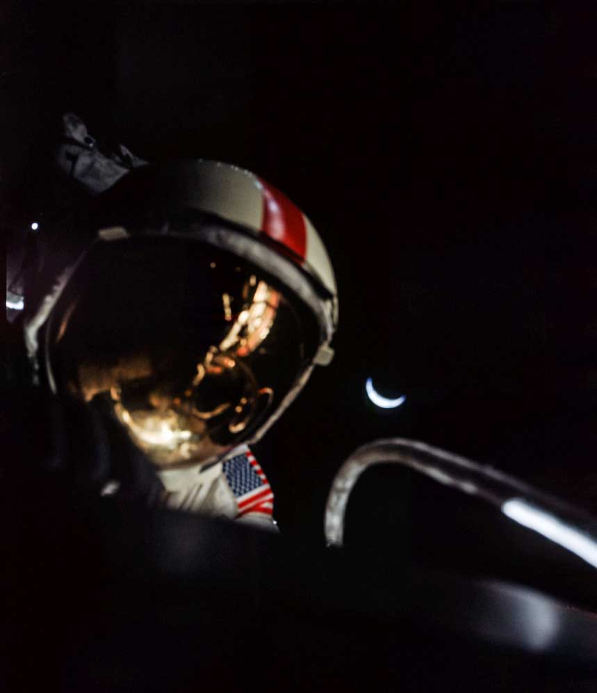 a closeup of an astronaut's helmet with the moon in the background