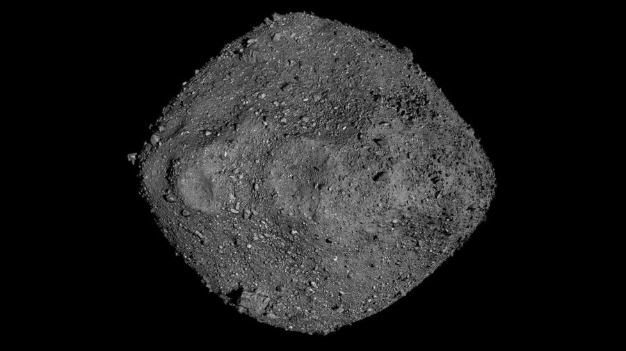 A diamond-shaped grey asteroid with ridges, holes, and craters in it, against a black background