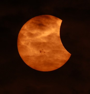Image of partial solar eclipse as seen through clouds