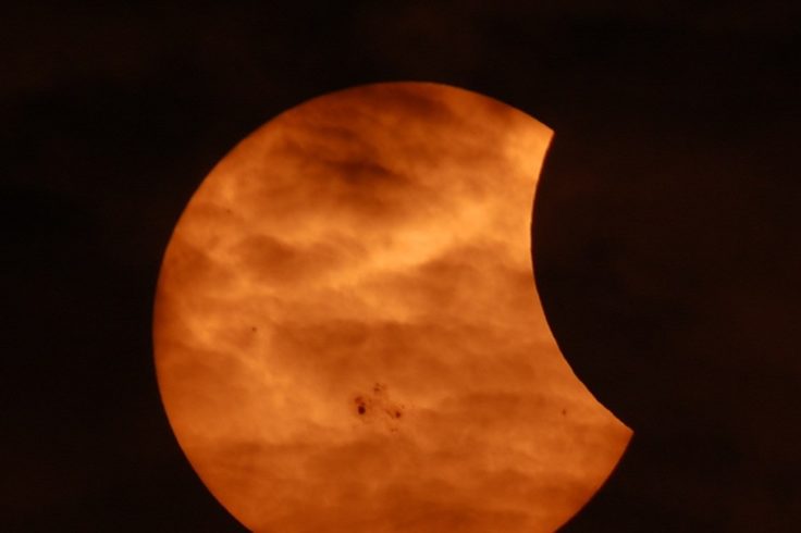 Image of partial solar eclipse as seen through clouds