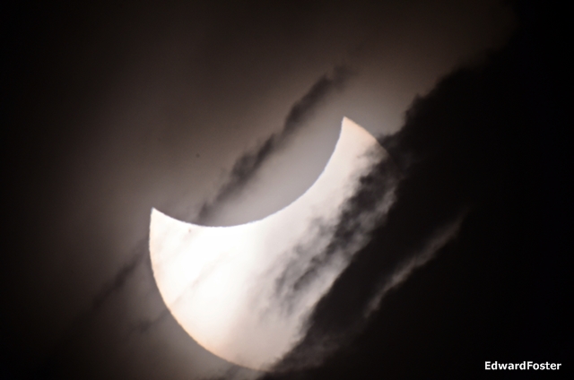 Crescent Sun partially blocked by clouds