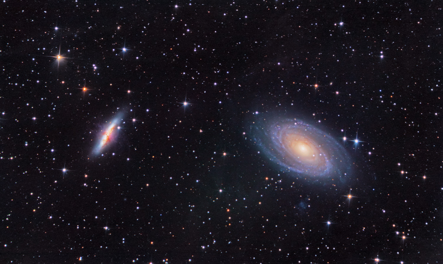 Two galaxies, one mostly edge-on and one mostly face-on, on a star-spotted field