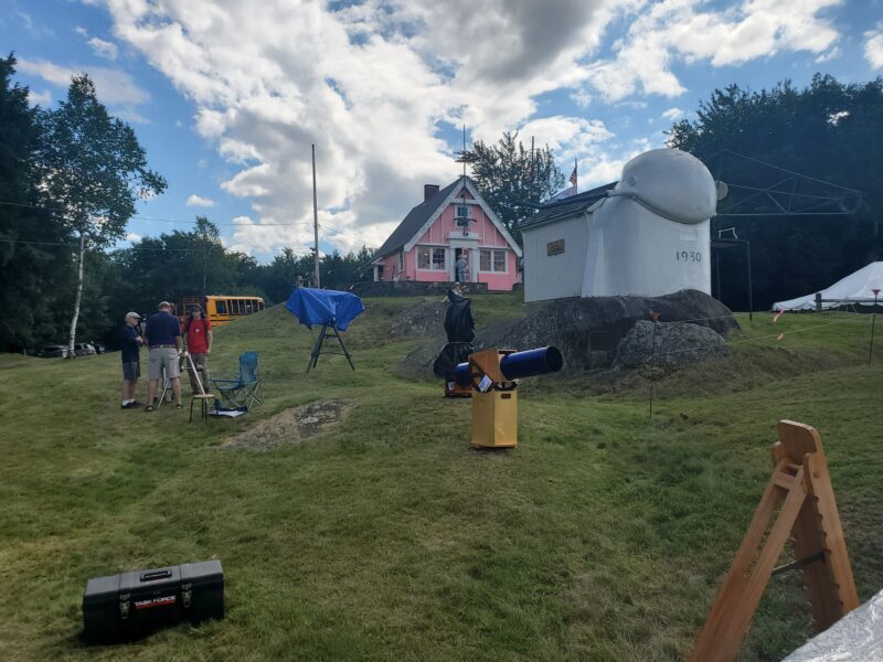 A mostly empty field with a few telescopes on it below a pink building and the Porter Turret telescope