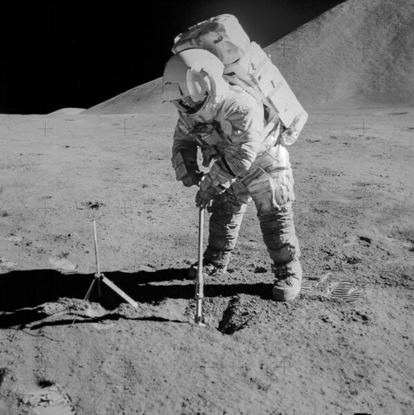 astronaut places tool into ground on lunar surface