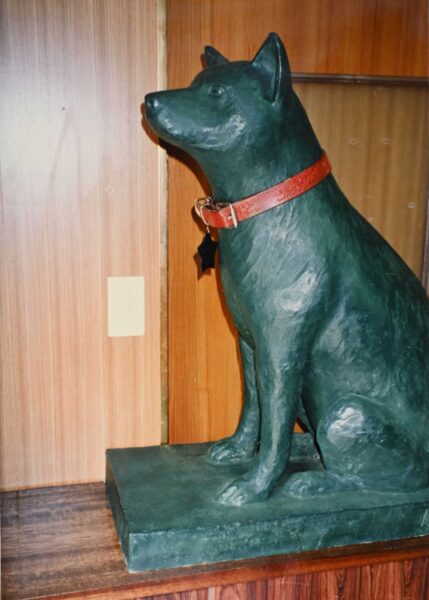 a side view of a grey-green statue of a sitting dog