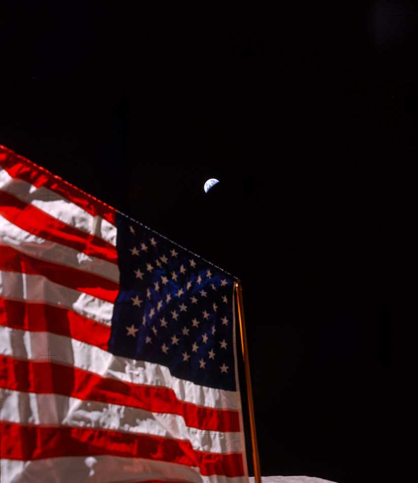 american flag in the foreground with the moon in the far off background