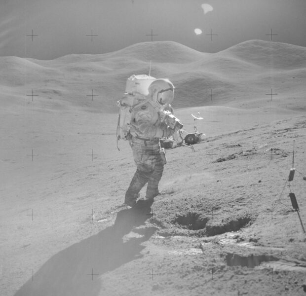 A bright glare shown as an astronaut walks the lunar surface with the sun visor down on his suit