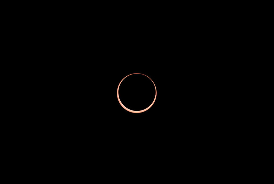 a thin circle of yellow light around a black circle on a black background