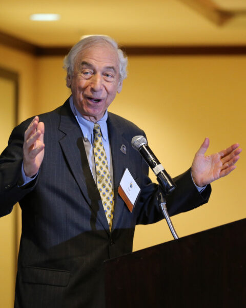 a man stands at a podium in suit speaking into a microphone