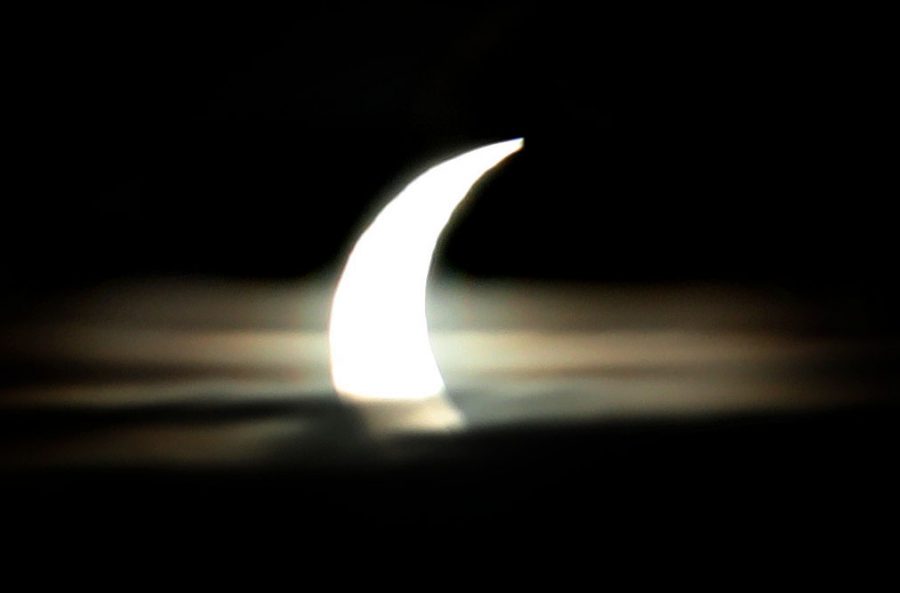 Partial solar eclipse above clouds