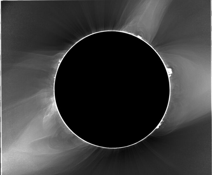 Totality in black-and-white shows smokey swirls of corona outside of the Moon's disk
