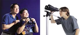 Man with woman holding binoculars; man at binocular mount