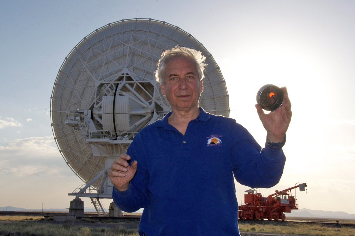 a man standing in front of a large satellite dish