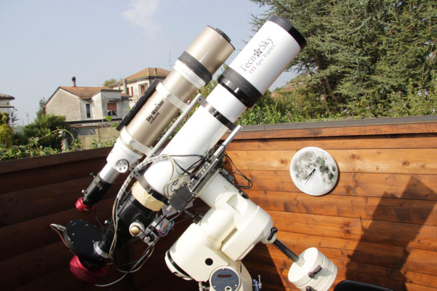 a telescope on a deck with a house and trees in the background