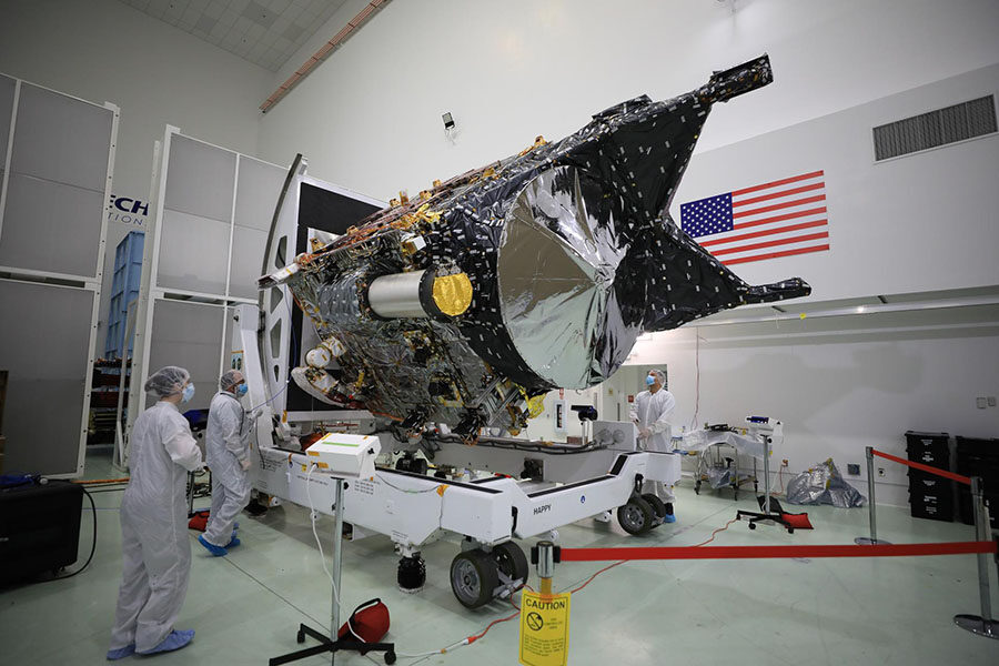 Psyche spacecraft in the clean room with two engineers in bunny suits