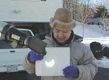Sky & Telescope image archivist Imelda Joson shows how to safely view a partial eclipse of the Sun on Christmas day, 2000. She demonstrates the projection method of solar viewing by projecting the eyepiece image onto a white card.