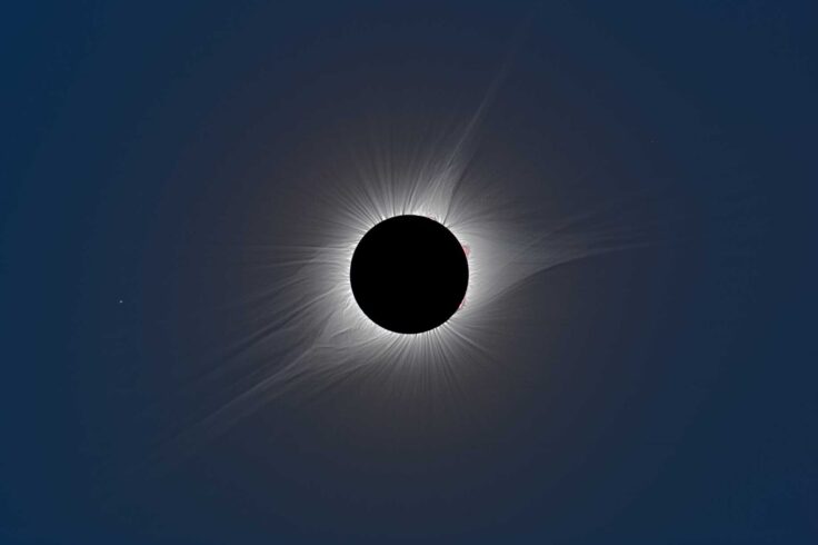 a black circle with a halo of light around it radiating outward on a dark blue background