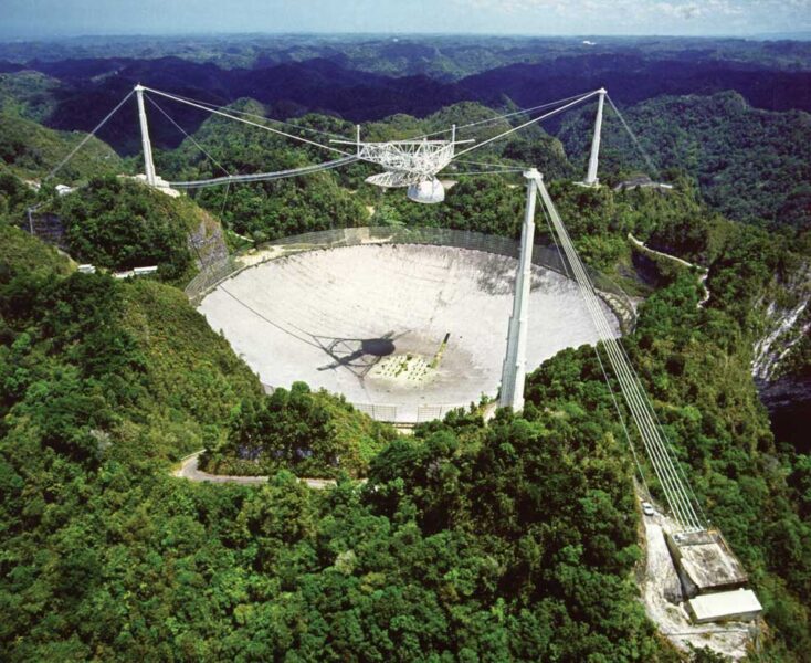 an aerial shot of a large cement disc in the midst of trees