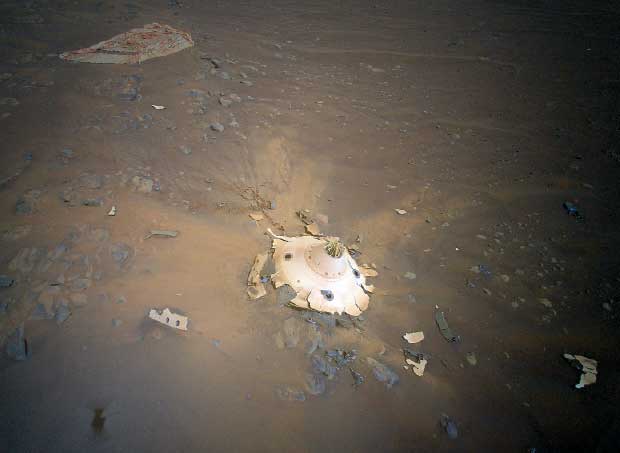 the broken remains of white machinery in the center of orange and grey dust