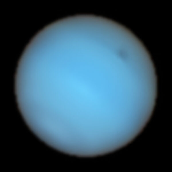 large blue planet with a dark spot near its northern pole