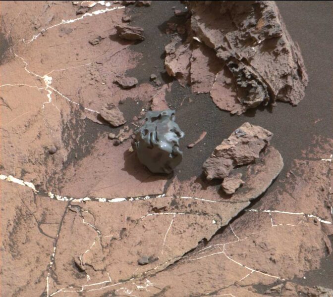 a small grey rock like object against a rocky terrain orange background