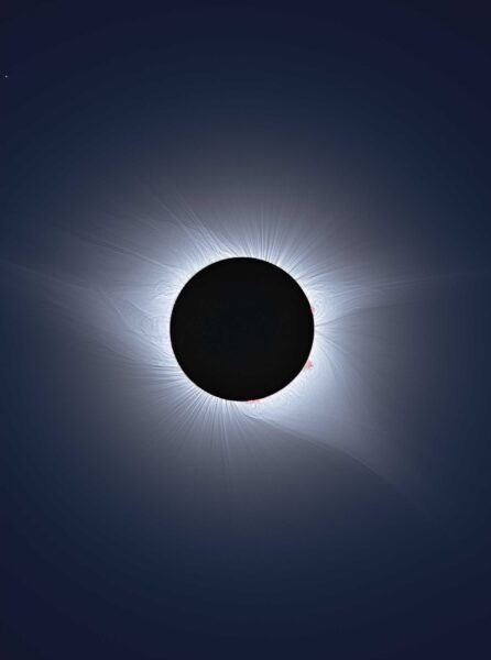 a black circle in the middle is surrounded by a ring of light against a dark background